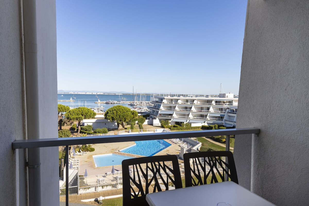 A balcony with a view of a marina, pool, and hotel buildings.