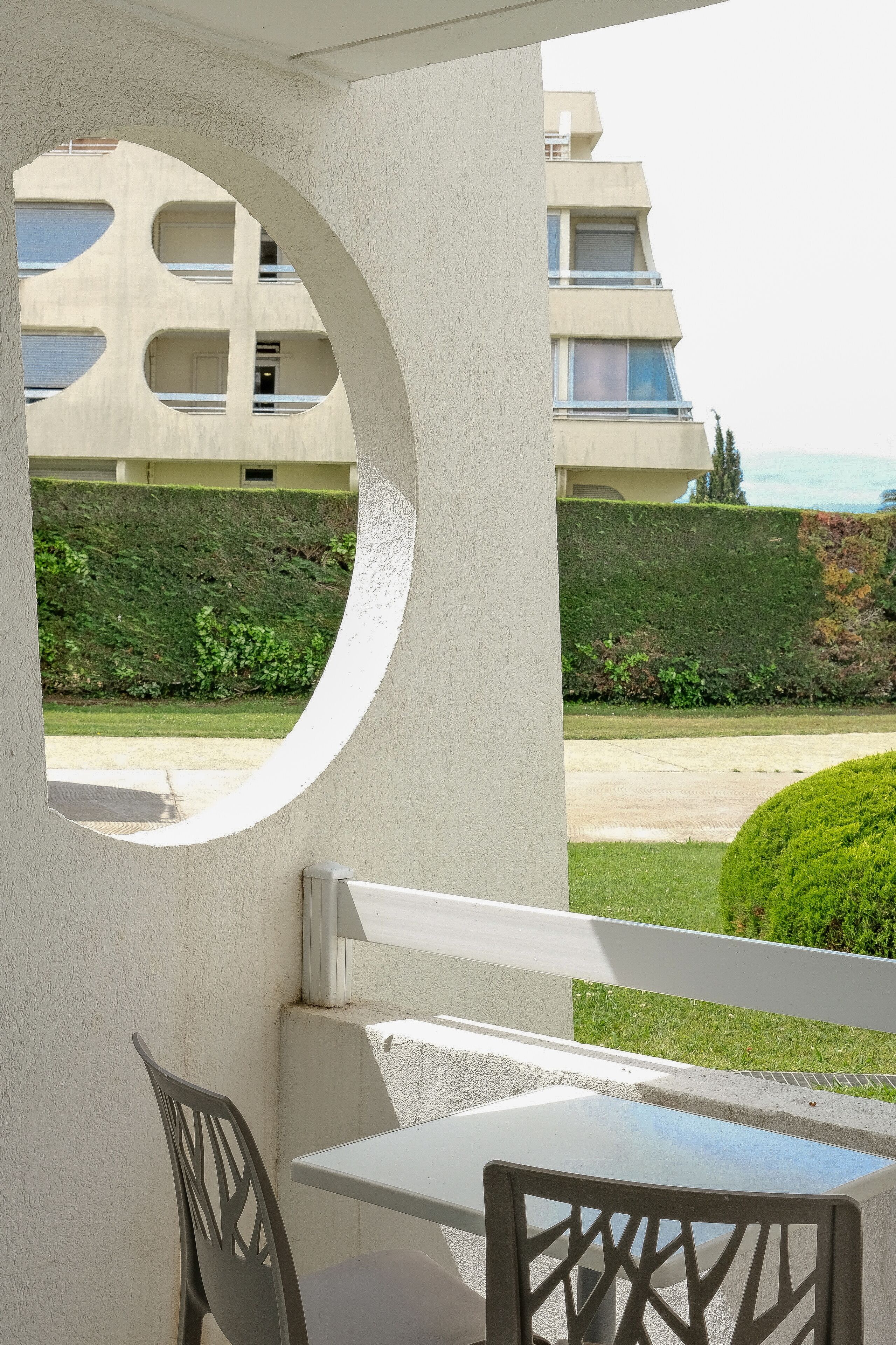 A balcony with a round window, a table, and two chairs.