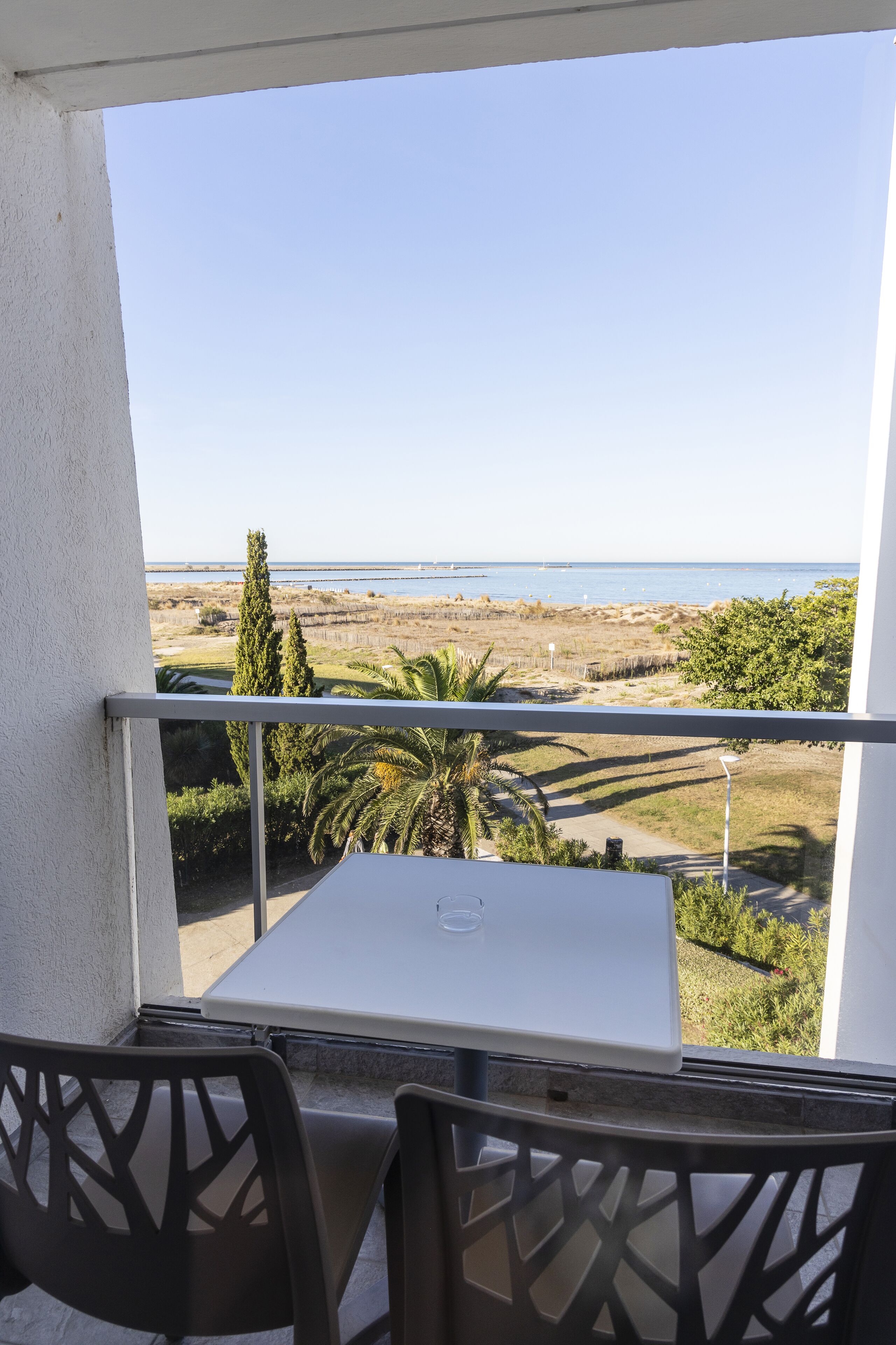 Un balcón con mesa y sillas, con vista a una playa y al océano.