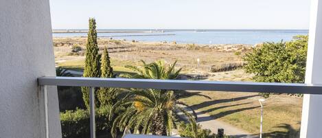 Un balcón con mesa y sillas, con vista a una playa y al océano.