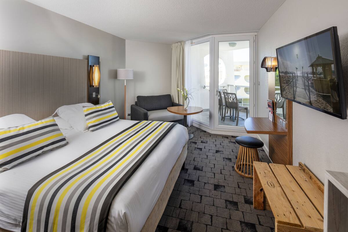 A hotel room with a bed, a sofa, a small table, and a bench.