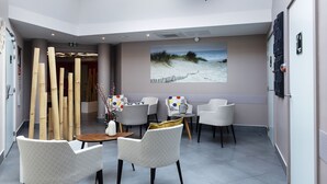 A spacious room with a high ceiling and skylight, featuring modern furniture and a large painting. - Hôtel & Spa - Thalazur Port Camargue (Le Grau-Du-Roi)