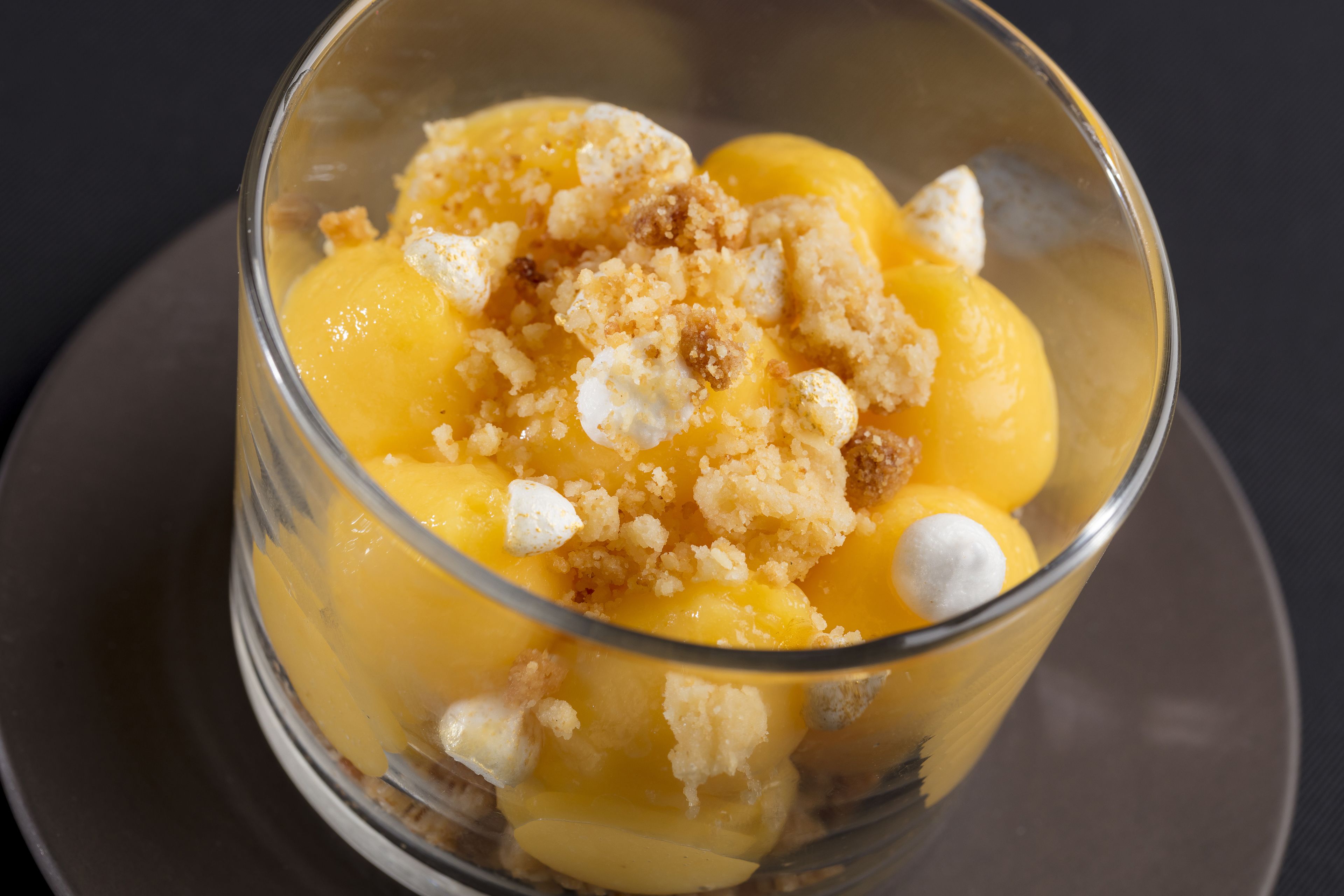 Un postre en un bol de vidrio transparente con cobertura desmenuzada y malvaviscos.