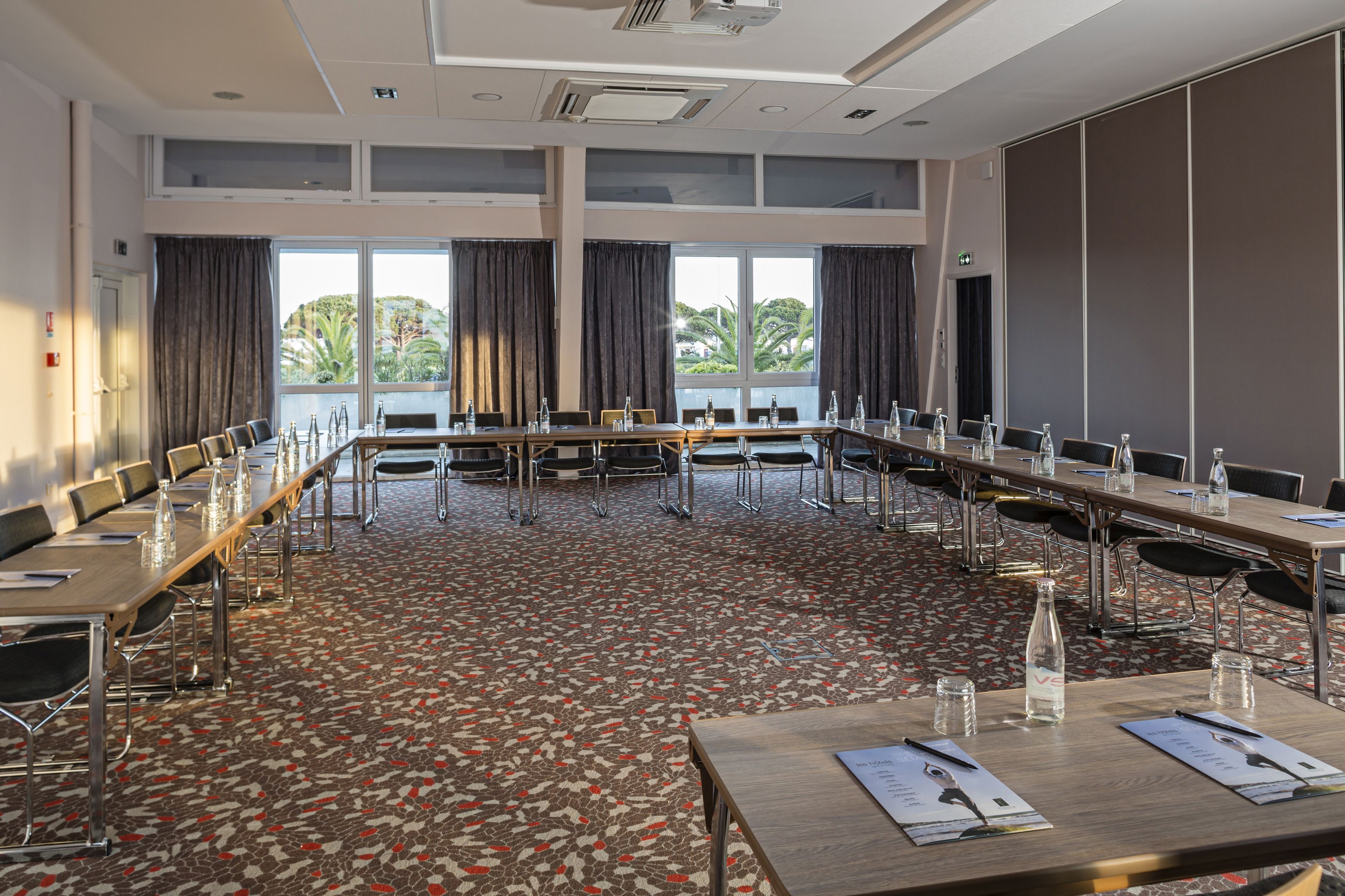 Uma sala de conferência com uma mesa comprida, cadeiras e uma tela de projeção.