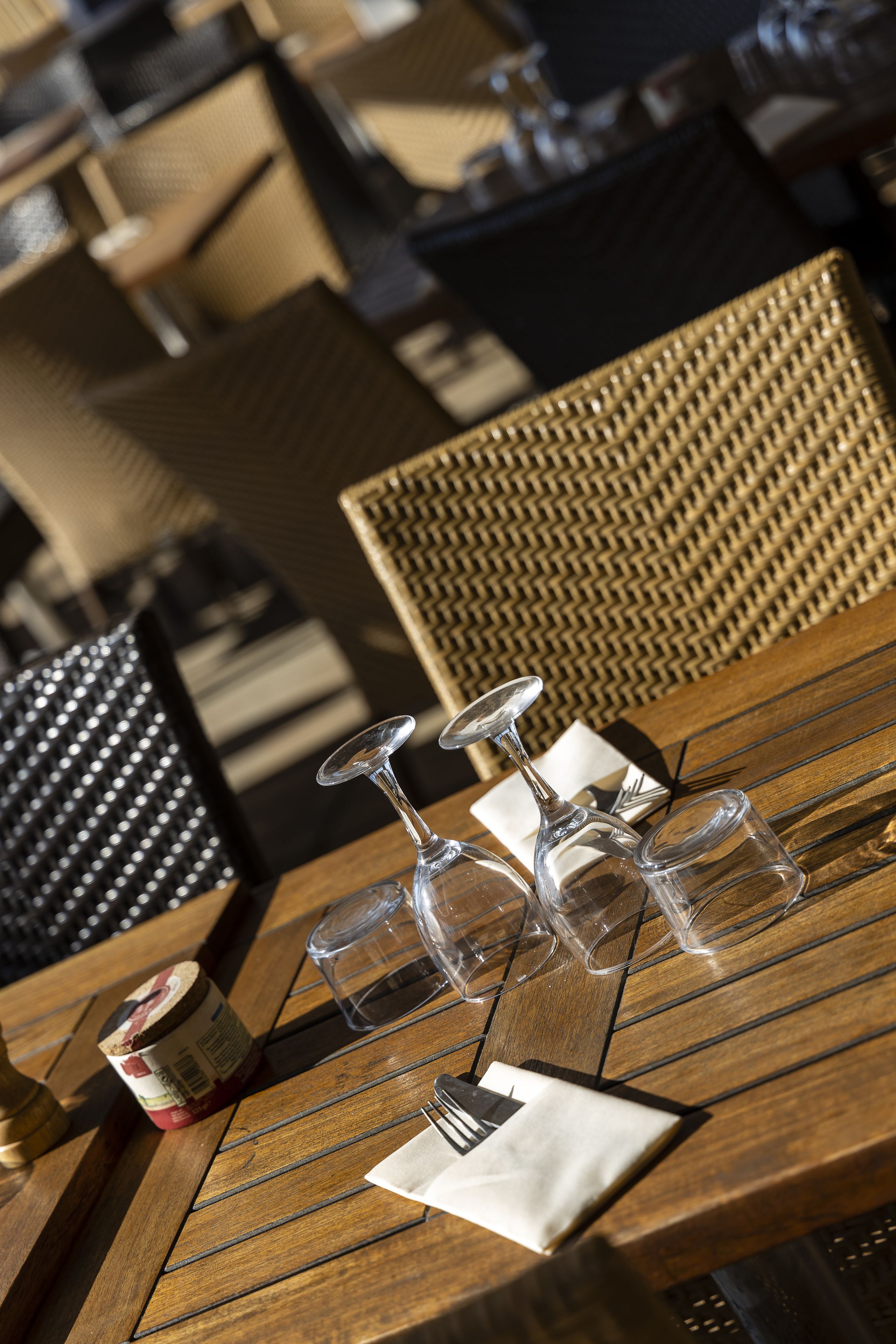Een houten tafel met een fles saus, een vork en drie wijnglazen.