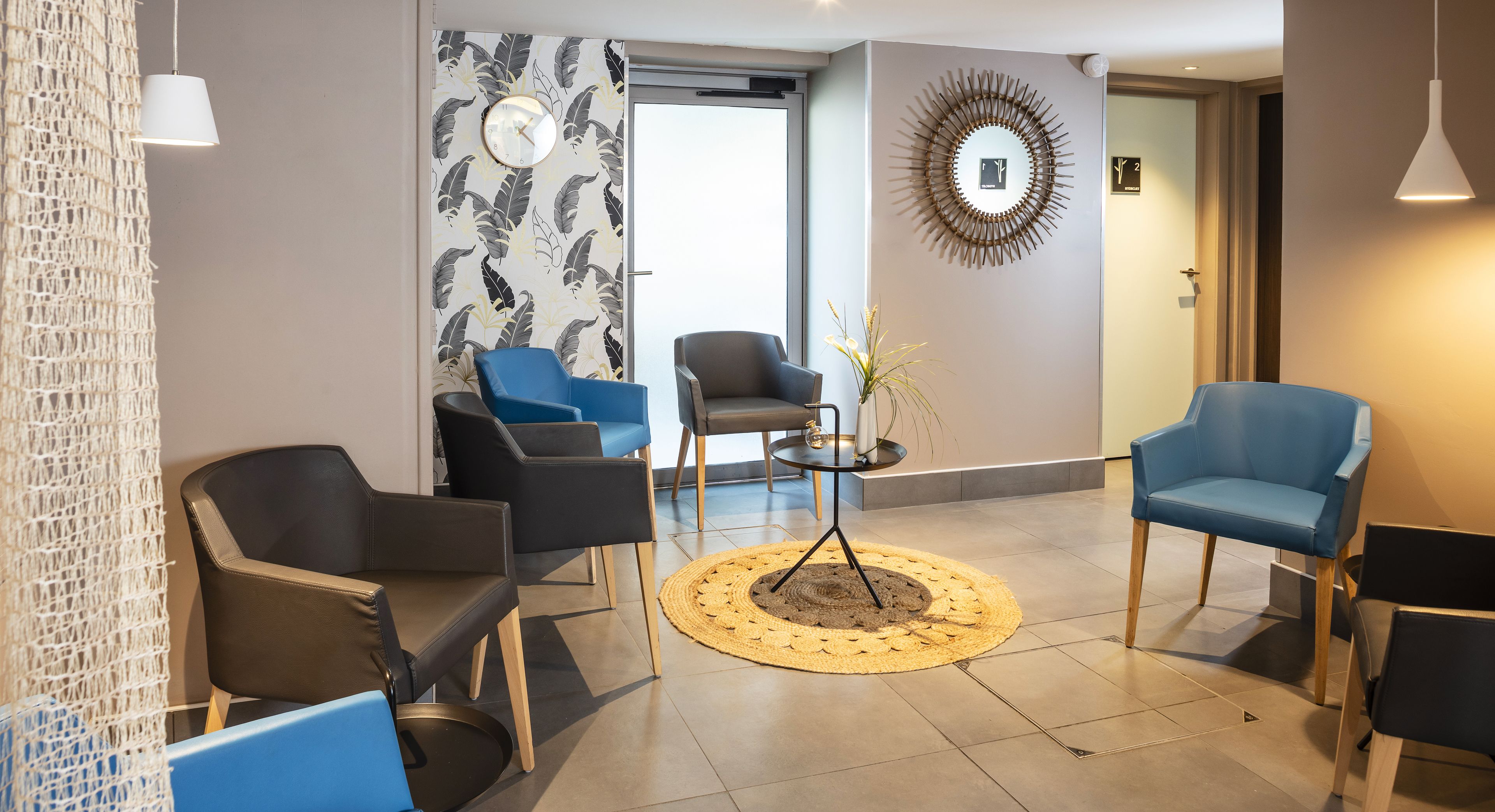 A modern waiting area with four chairs, a round table, and a decorative wall clock.