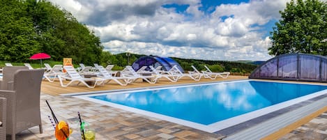 Una piscina al aire libre de temporada, sombrillas