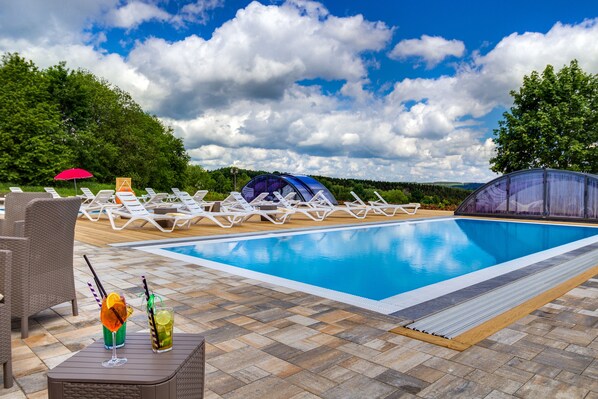 Una piscina al aire libre de temporada, sombrillas