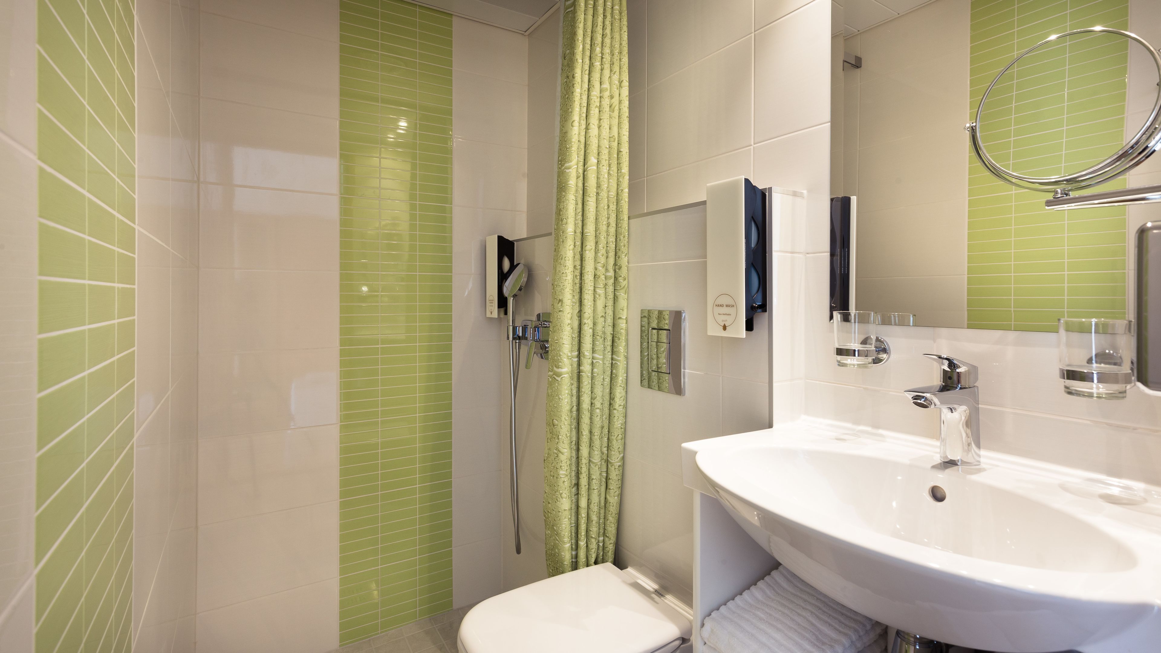 A modern bathroom with a shower, toilet, sink, and a hand wash station.