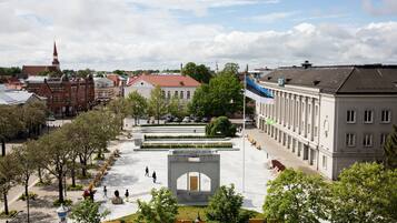 A spacious public square with a central monument, surrounded by trees and buildings.