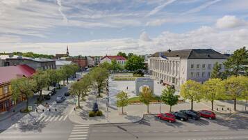 A city street with buildings, trees, and parked cars.