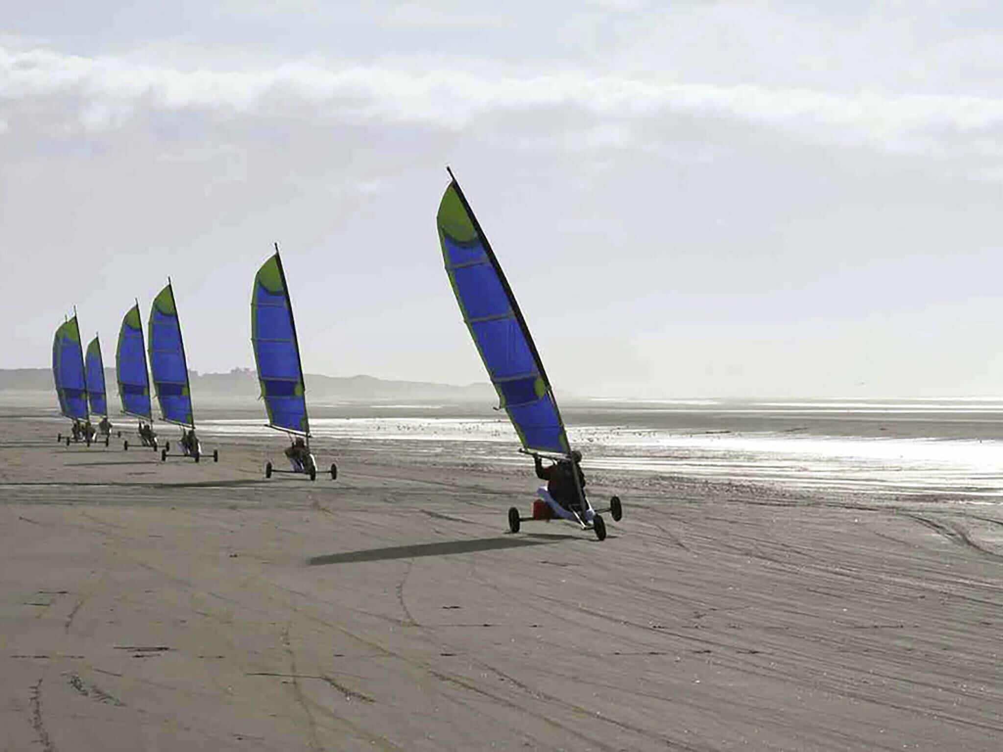 Ein Strand mit mehreren Windsurfbrettern und Windsurfern.