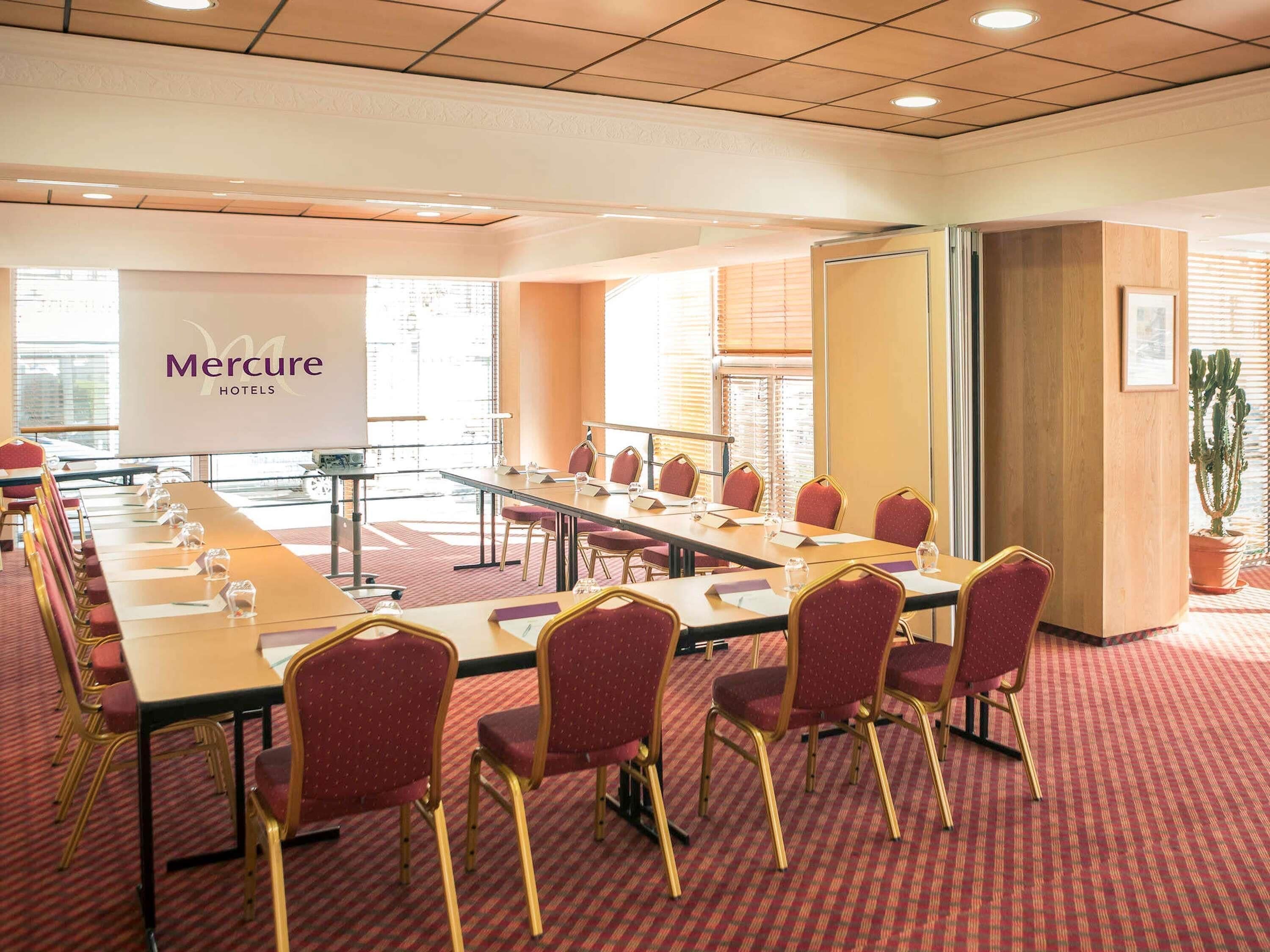 A conference room with a long table, red chairs, and a whiteboard.