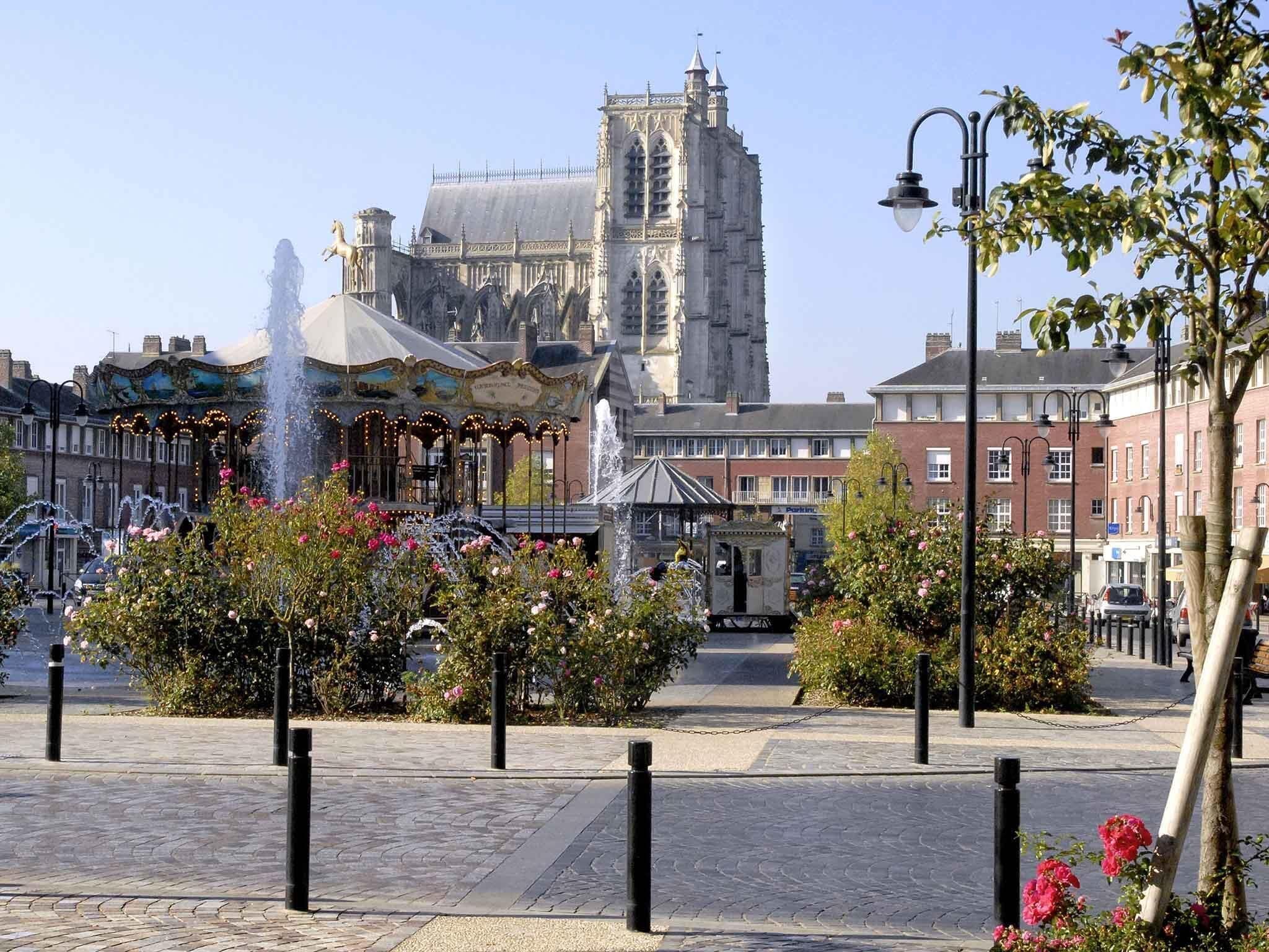 A historic building with a prominent tower, a decorative fountain, and a carousel.