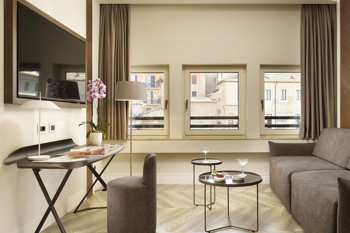 Een moderne woonkamer met een bank, een bijzettafeltje en een aan de muur bevestigde televisie.
