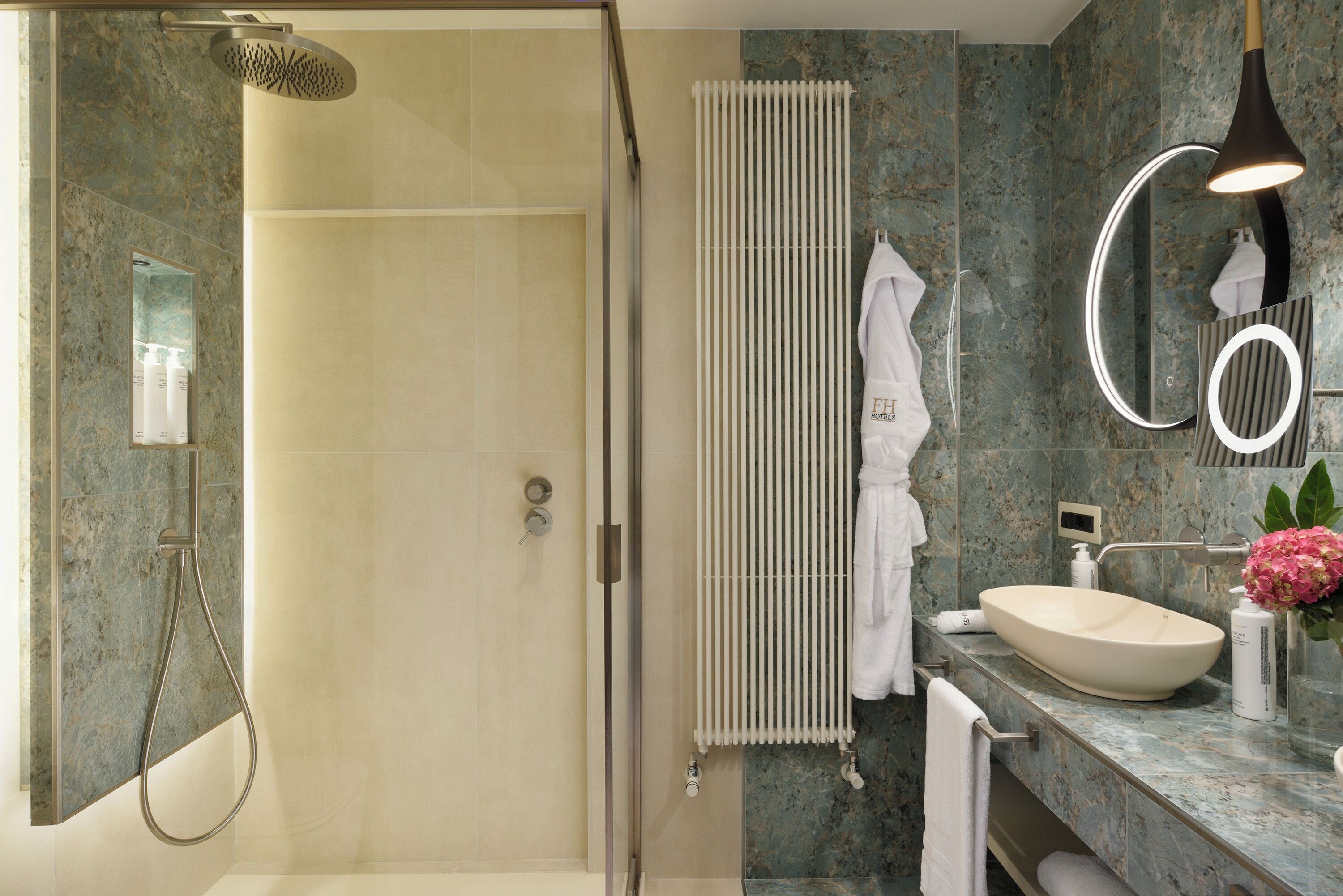 A modern bathroom with a glass-enclosed shower, a white sink, a marble countertop, and a towel rack.