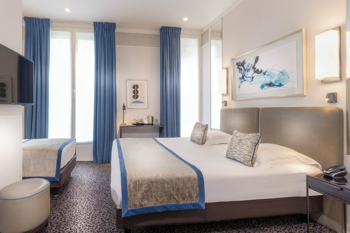 A hotel room with a large bed, a desk, a chair, and a TV.