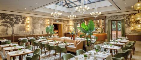 A spacious dining area with high ceilings, chandeliers, and a view through a skylight.