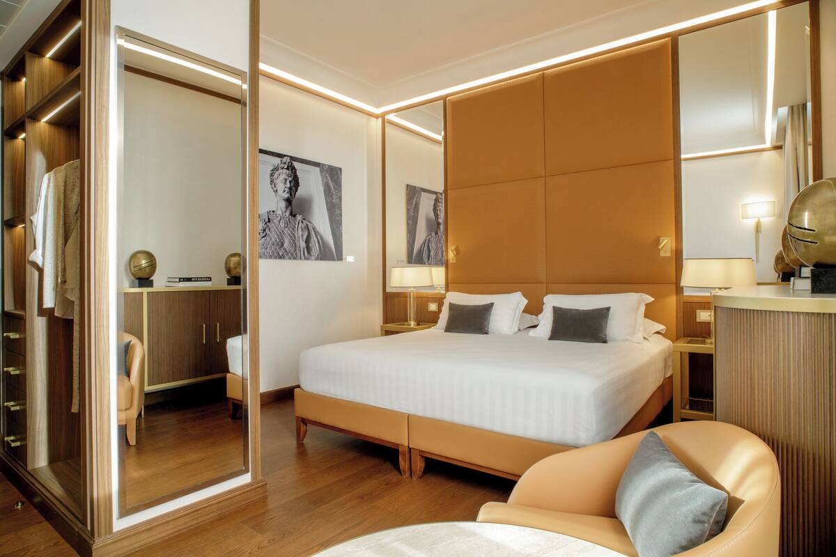 Una camera d'hotel con un letto grande, un armadio, un'area salotto e uno specchio.