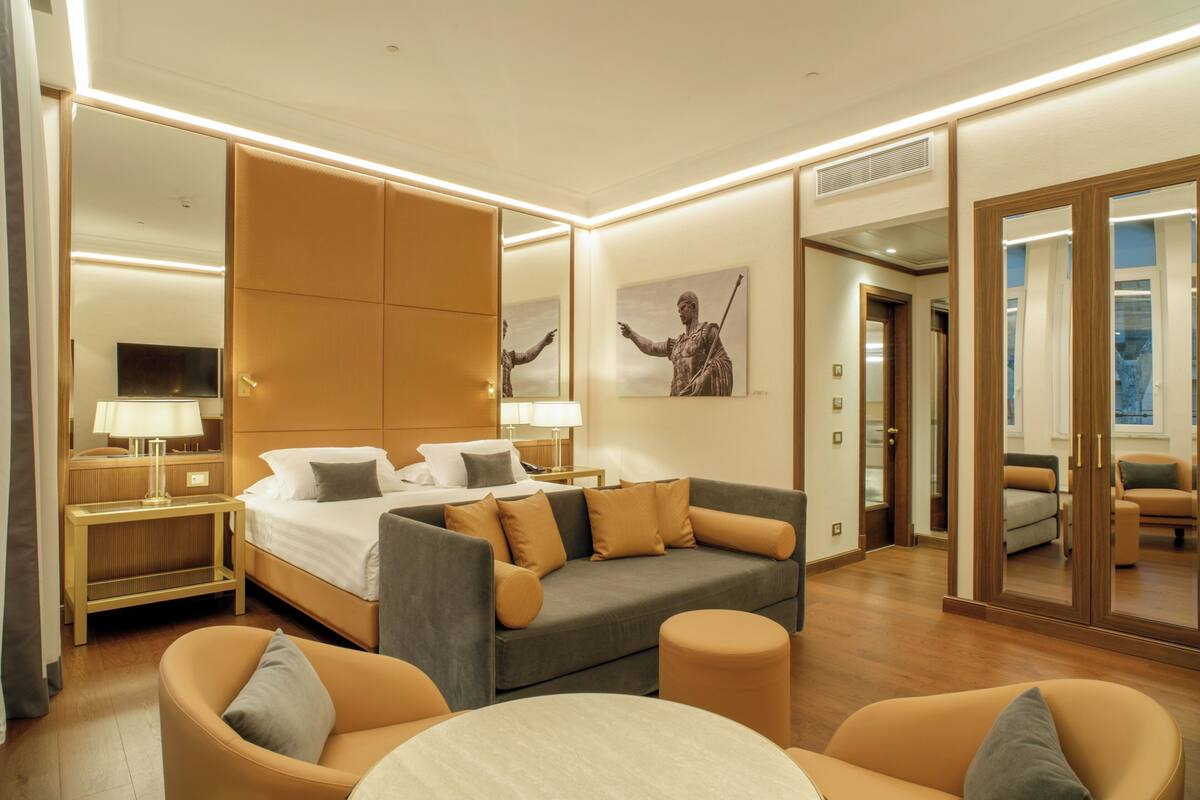 Una camera d'albergo moderna con un letto grande, un divano, un tavolino rotondo e una televisione.