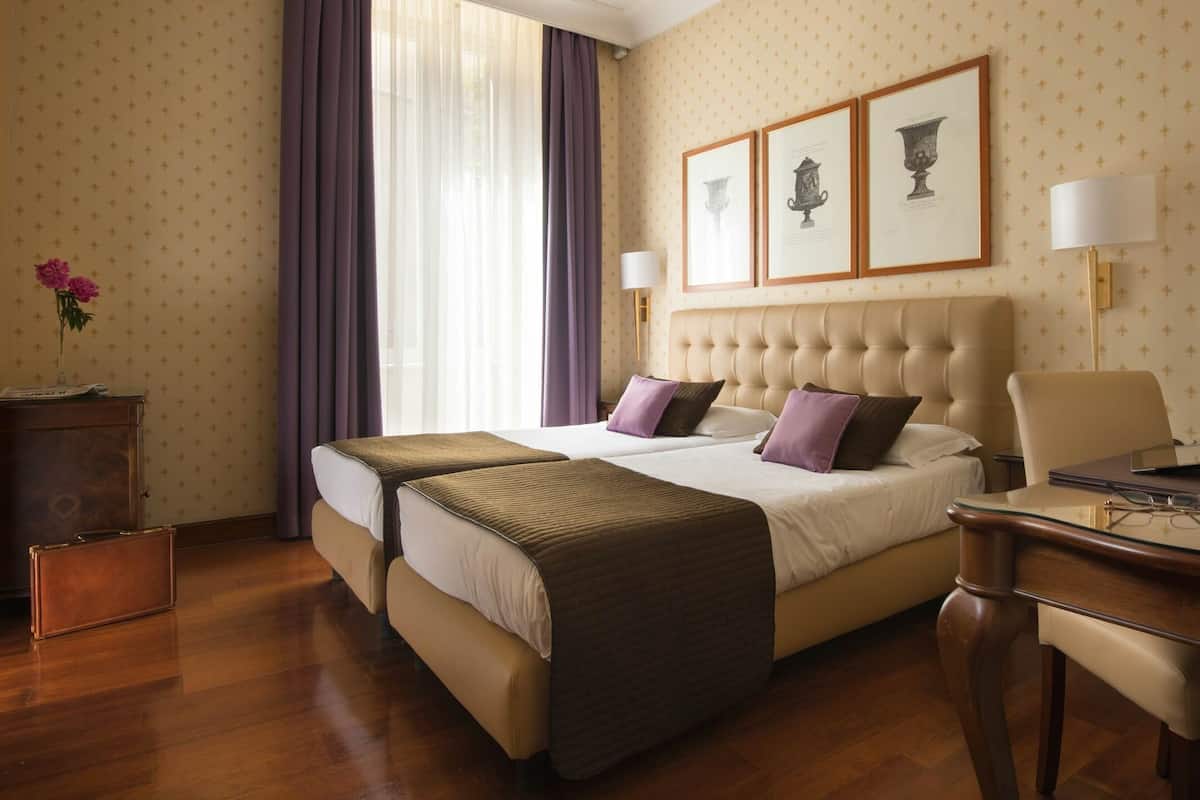 A hotel room with a large bed, two bedside tables, a desk, and a chair.