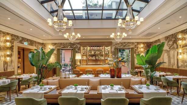 Un restaurante espacioso con techo alto, candelabros y una zona de bar central.