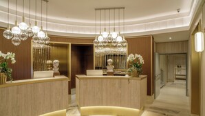 Un área de recepción con un mostrador curvo, candelabros y una estatua.