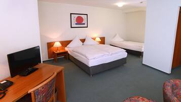 A hotel room with a bed, a desk with a computer, a chair, and a TV.