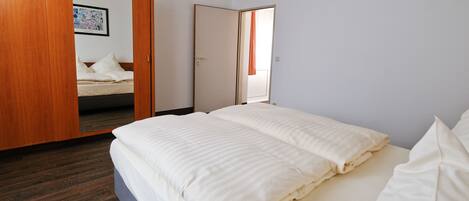 Un dormitorio con cama, armario de madera y una puerta que da a otra habitación.