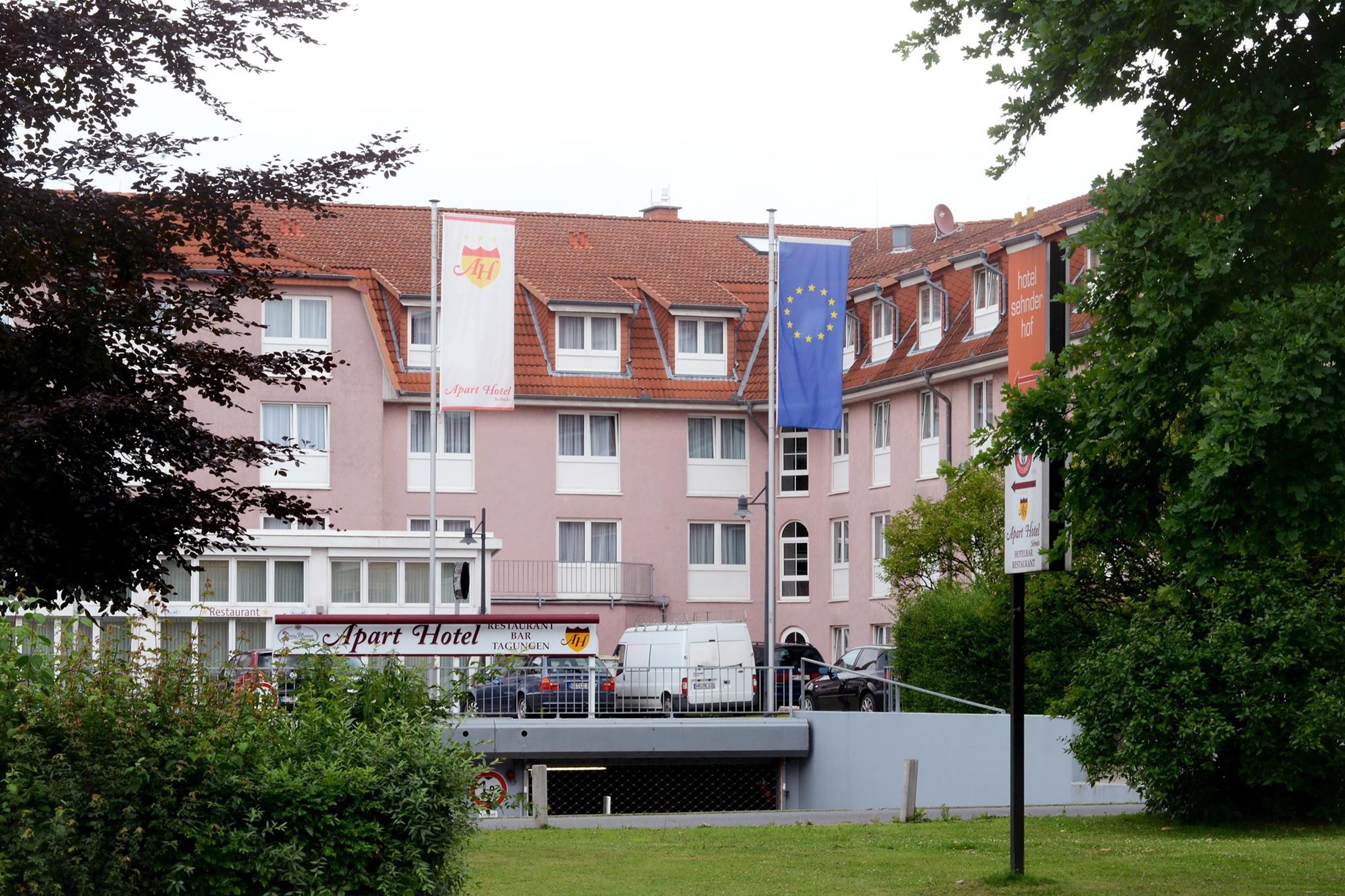 A multi-story building with a red-tiled roof, featuring a restaurant and an 'Apart Hotel' sign.