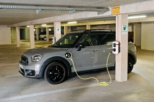 A parking garage with a Mini Cooper charging at a station.