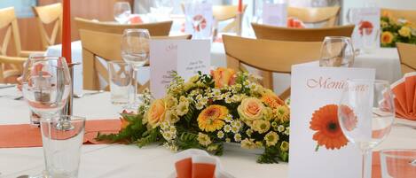 A dining table set with glassware, a menu, and a floral centerpiece.
