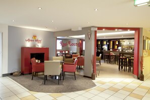 Een hotellobby met een open haard, zithoek en een bar/loungeruimte.