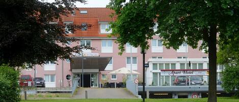 A building with a red roof, a sign for 'Apart Hotel', and a covered entrance.