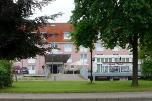 Un edificio con techo rojo, un cartel que dice 'Apart Hotel' y una entrada cubierta.