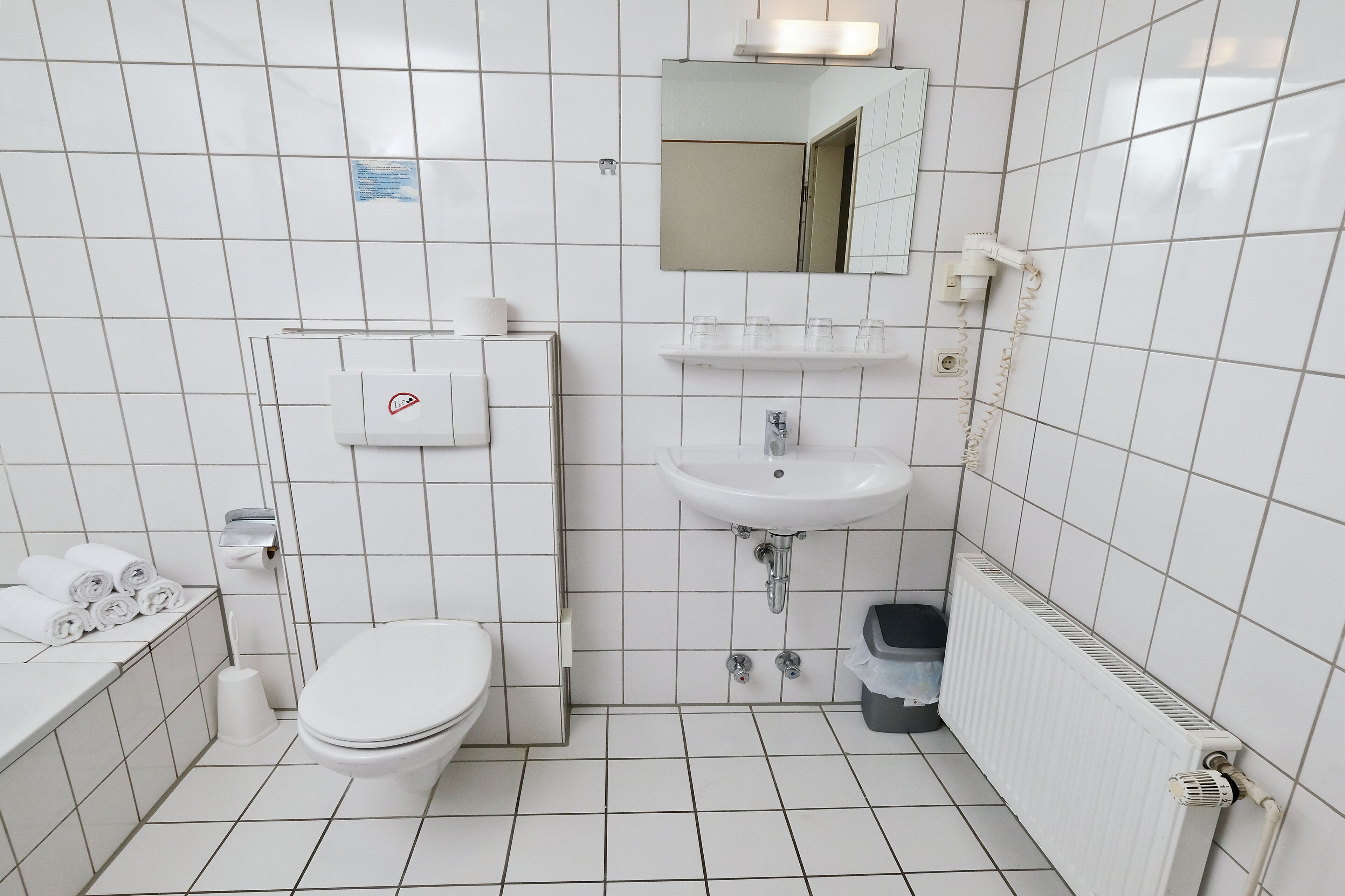 A small, clean bathroom with a toilet, sink, and mirror.