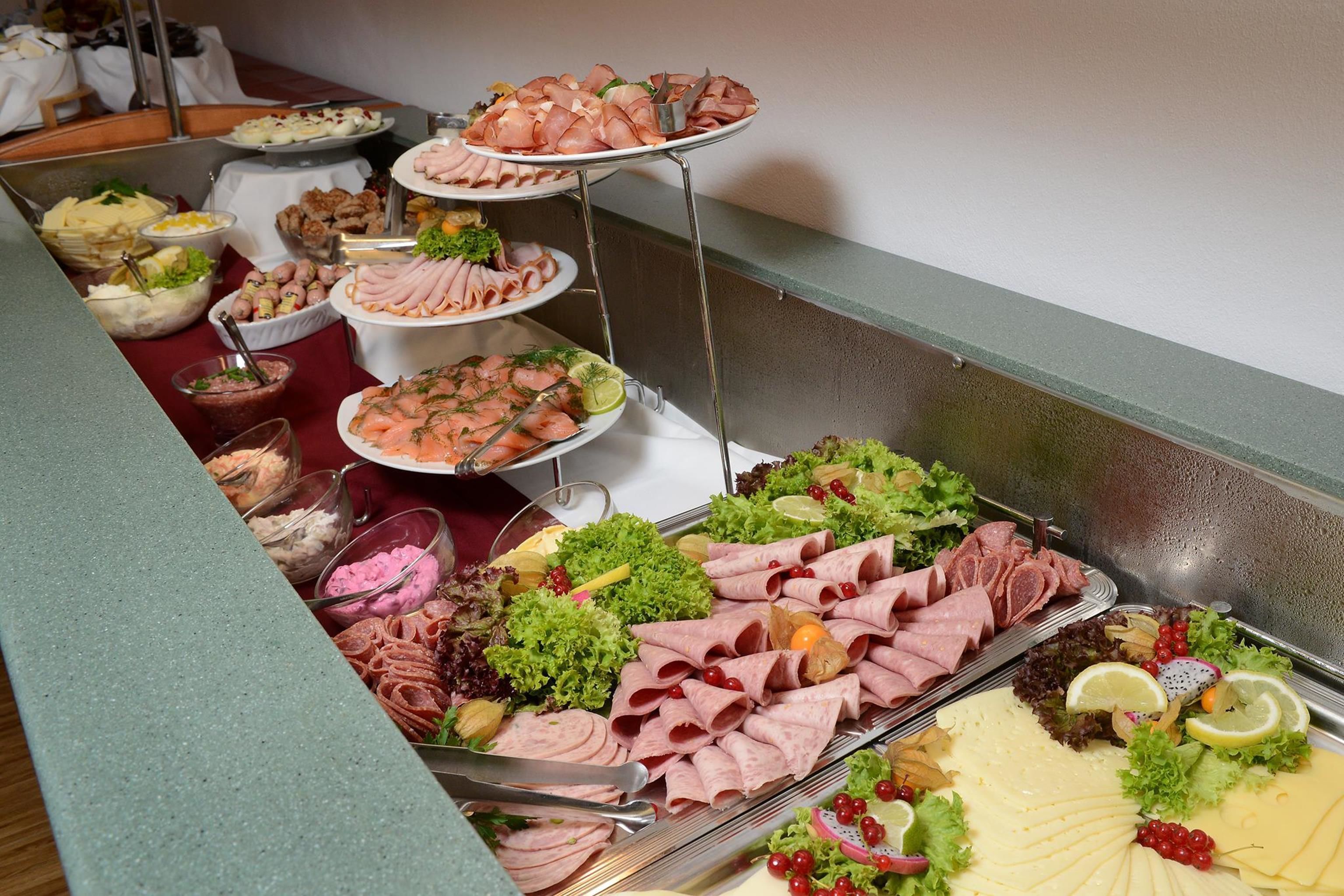 A buffet with various food items including meats, cheeses, and salads.