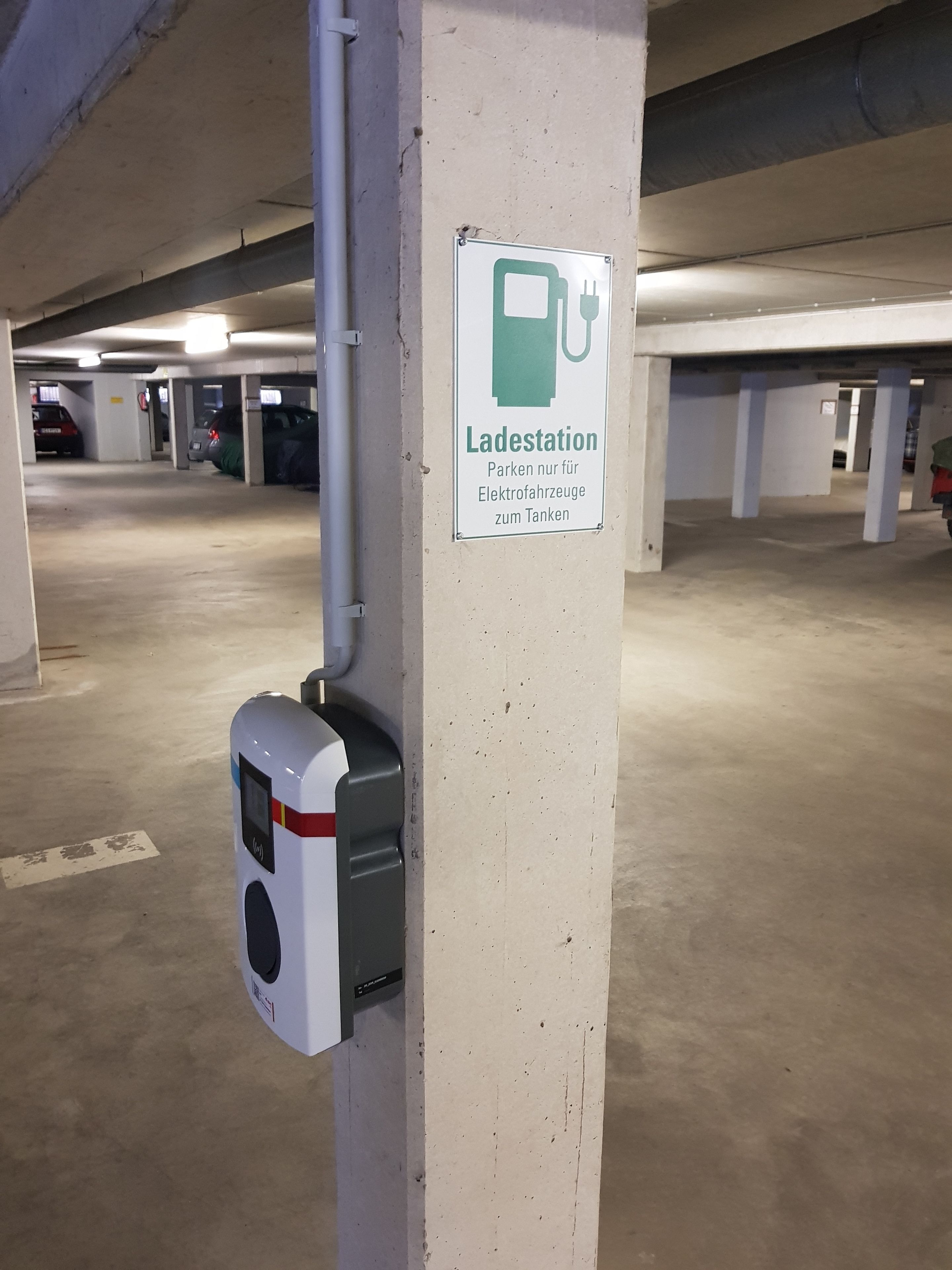 A parking garage with a sign indicating a charging station for electric vehicles.