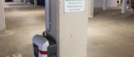 A parking garage with a sign indicating a charging station for electric vehicles.