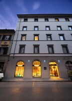 Un hotel a più piani con una facciata moderna, caratterizzato da finestre ad arco e un ingresso al piano terra con insegne illuminate.
