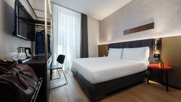 Una habitación de hotel moderna con una cama grande, un escritorio con televisor, un espejo y un cartel que dice 'PASSION'.