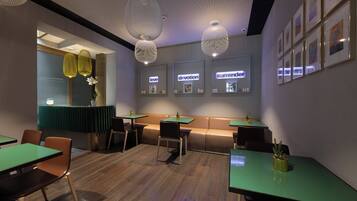 A modern restaurant interior with booths, green tables, and pendant lighting.