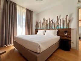 Un letto grande con testiera in legno, pavimento in legno e finestra con tende.