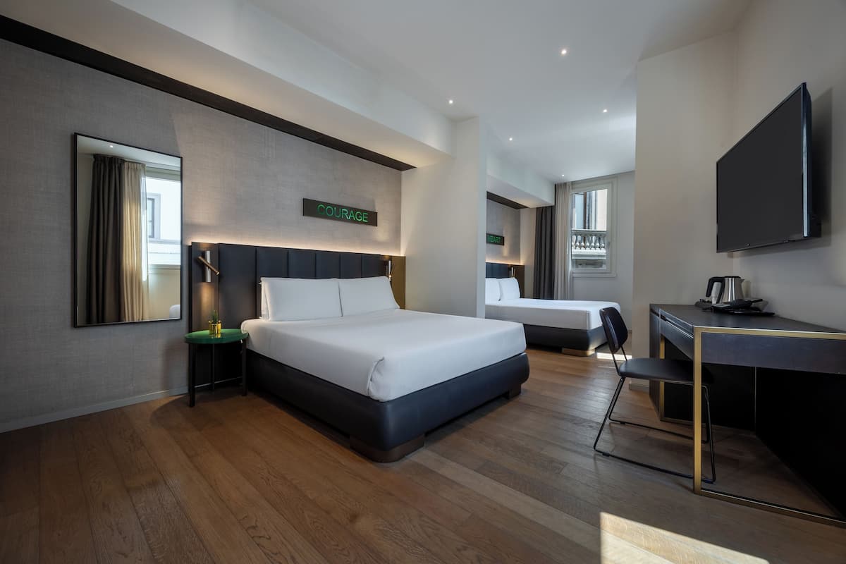 A modern hotel room with a large bed, a desk, and a television.