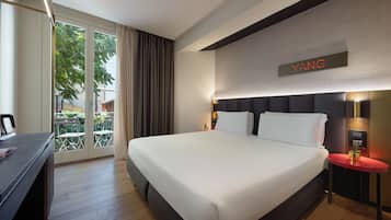 Habitación de hotel con una cama grande, un escritorio, una silla y vistas al exterior.