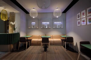 A modern interior with a green booth, two tables, and chairs, and wall-mounted artwork with words like "love" and "devotion".