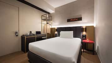 Una habitación de hotel moderna con una cama grande, mesitas de noche, un escritorio y un armario.