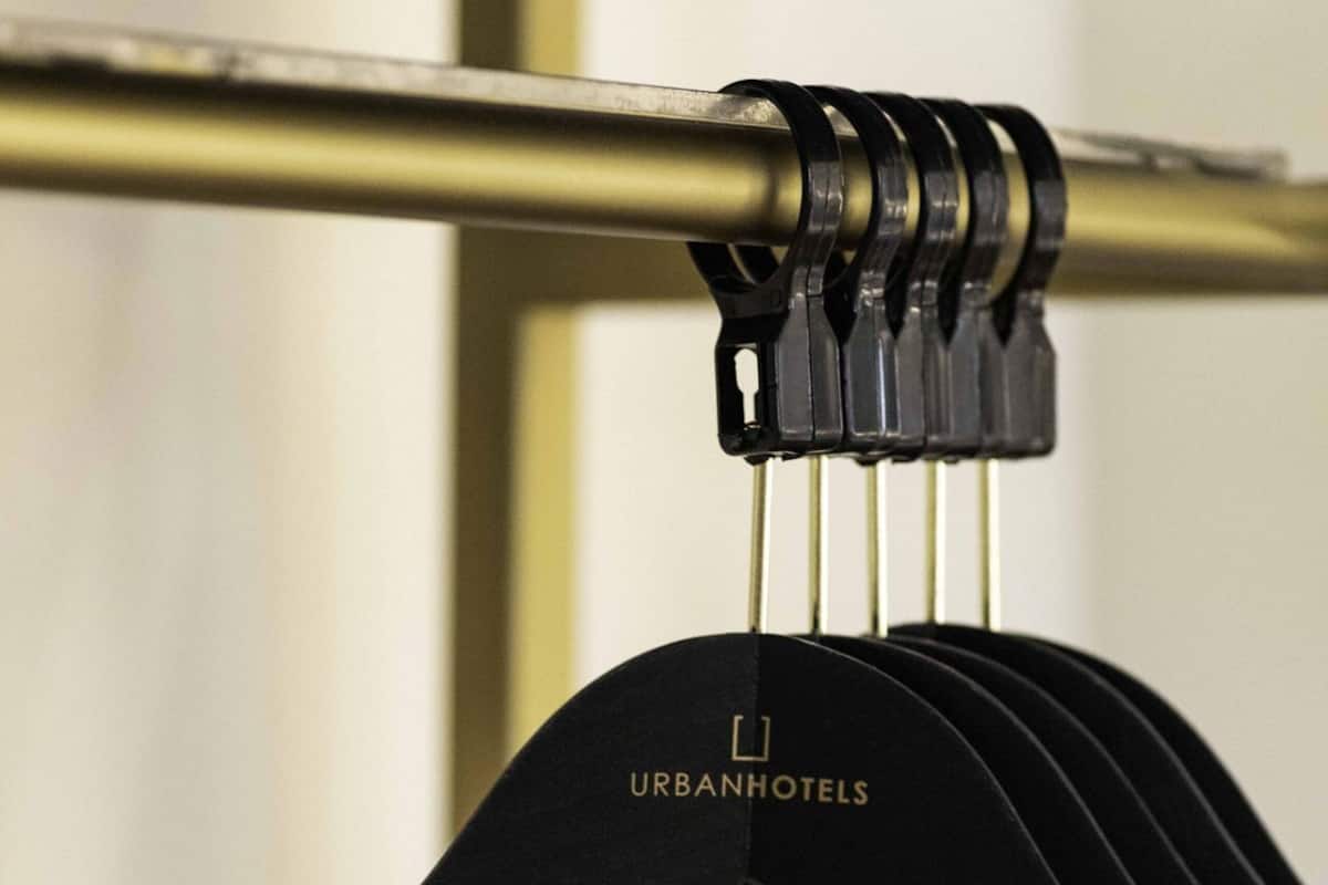 Un perchero negro con el texto 'URBANHOTELS', sujeto a una barra metálica.