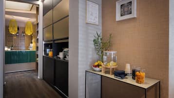 A modern hotel lobby with a reception desk, a bar area, and a seating space.