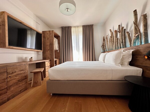 A bedroom with a large bed, wooden dresser, and a TV mounted on the wall. - The Market Urban Hotel (Florence)